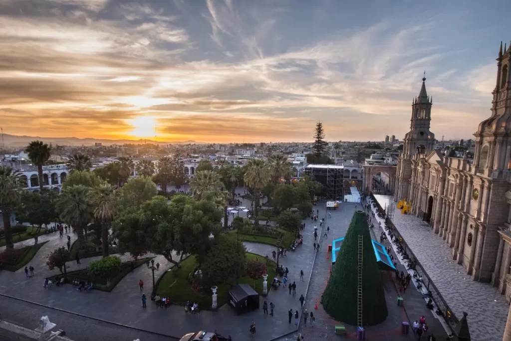 Panoramic view of Arequipa’s Plaza de Armas with the Cathedral, palm trees, and the Misti volcano in the background.