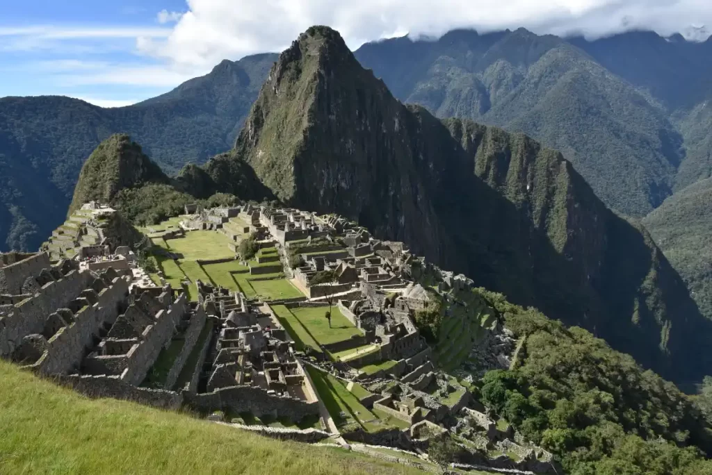 Vista panorámica de Machu Picchu, en Perú, rodeado de verdes montañas y antiguas ruinas incas.