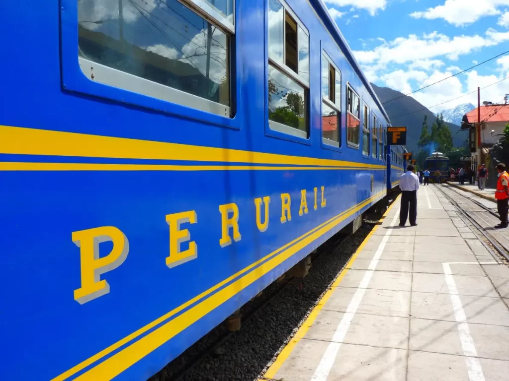 Tren de PeruRail en la estación esperando a que los turistas suban para el viaje a Machu Picchu.