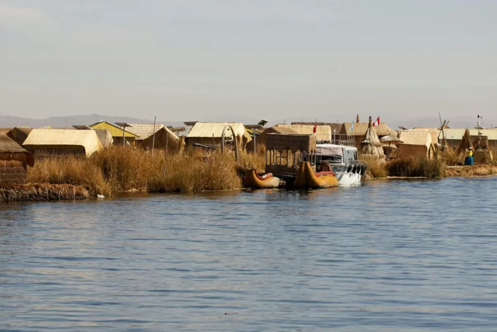 Traditional houses of a local community beside Lake Titicaca in Puno, Peru, surrounded by calm blue waters and natural landscapes.