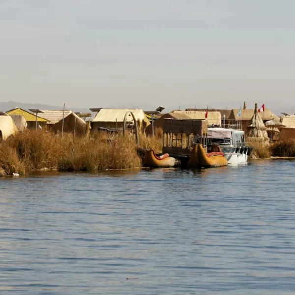 Traditional houses of a local community beside Lake Titicaca in Puno, Peru, surrounded by calm blue waters and natural landscapes.