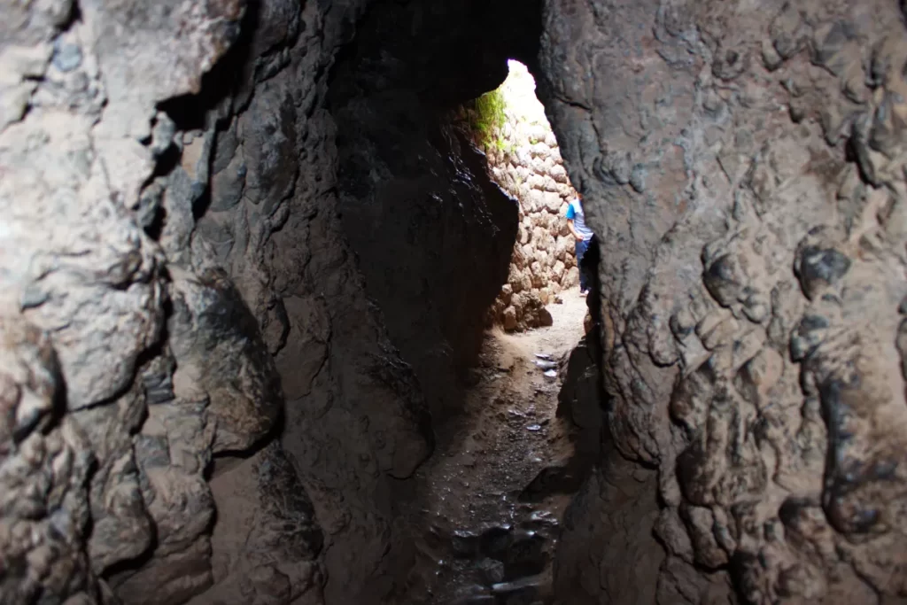 Inside the Inca Chinkana in Cusco (2025): Breakthrough Excavations Beneath Sacsayhuamán 14 Interior view of the Small Chinkana tunnel in Sacsayhuamán, Cusco, showing the exit illuminated by natural light, with blurred silhouettes of tourists outside.