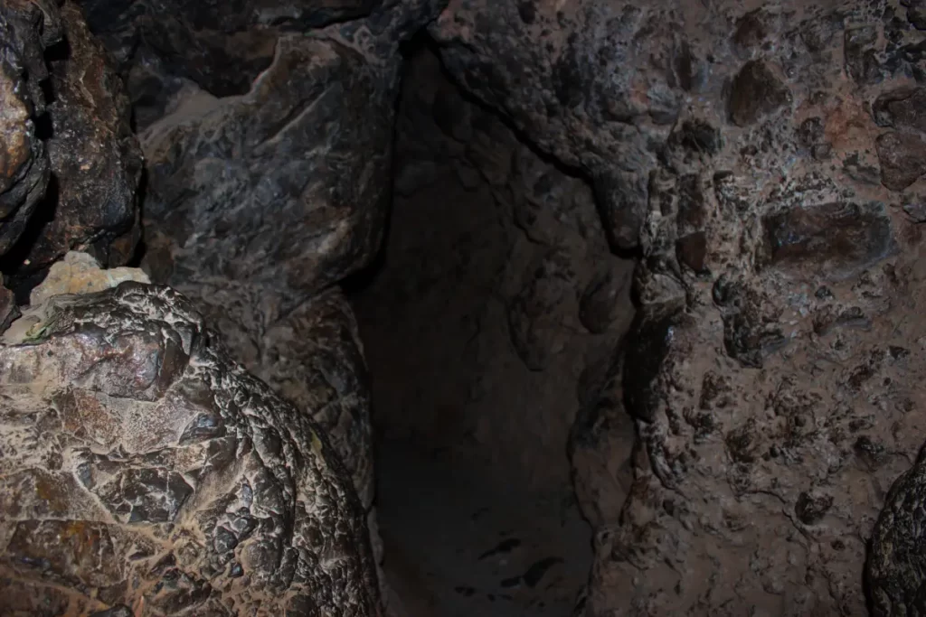 Inside the Inca Chinkana in Cusco (2025): Breakthrough Excavations Beneath Sacsayhuamán 12 Low-ceiling entrance passage of the Small Chinkana in Sacsayhuamán, Cusco, showing the narrow carved stone access where visitors need to crouch to proceed inside.